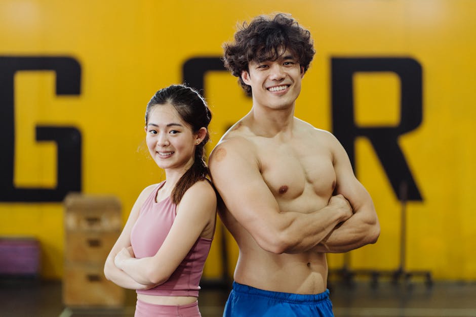 Smiling young man and woman in gym showcasing fitness and athleticism.